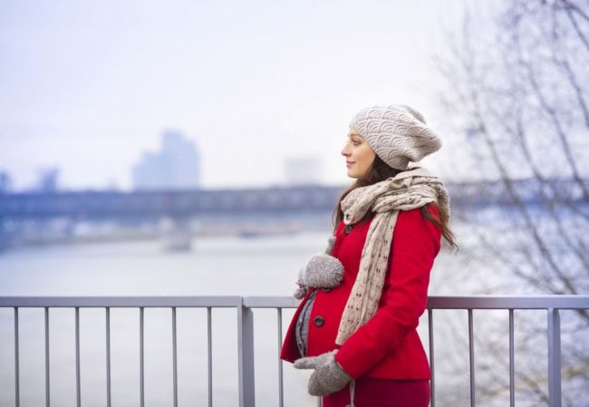 Беременная женщина гуляющая в холодное время года