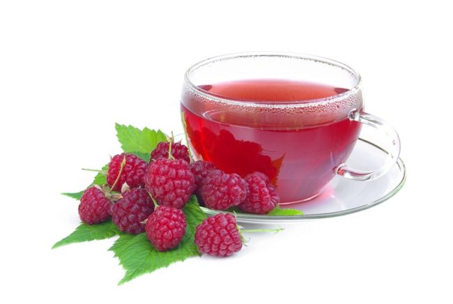 Малиновый чай в прозрачной чашке и ягода малина