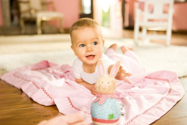 Девочка пяти месяцев в розовой одежде на полу