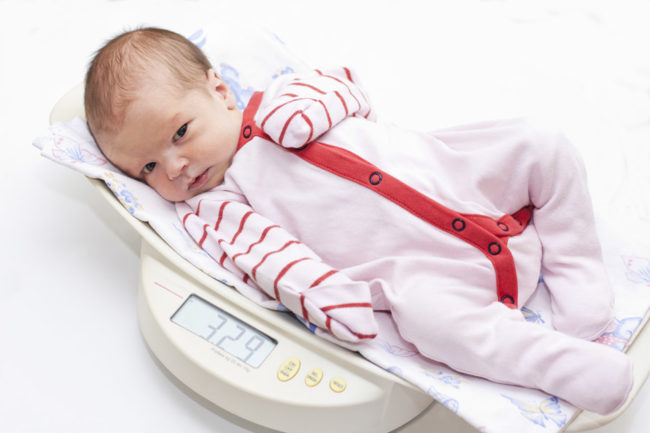 Новорождённый лежащий на весах