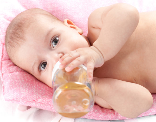 Новорождённый и сок в бутылочке
