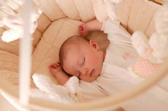 Спящий новорождённый в кроватке