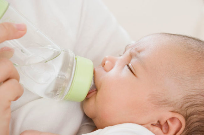 Новорождённый пьёт воду из бутылки