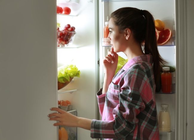 Женщина смотрящая в холодильник