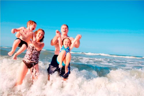 Семья купается в море, дети убегают от волны