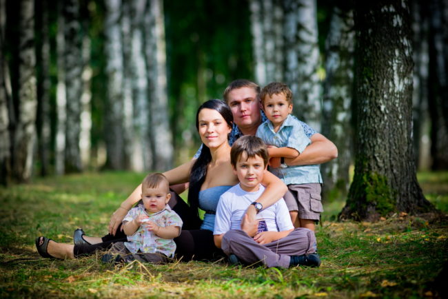 Большая семья сидит на лужайке позируют фотографу