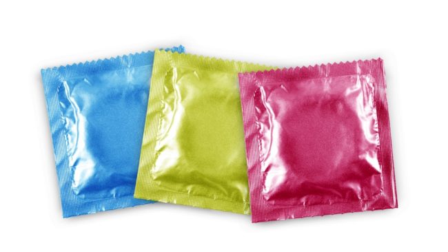 Презервативы в разноцветных упаковках на белом фоне