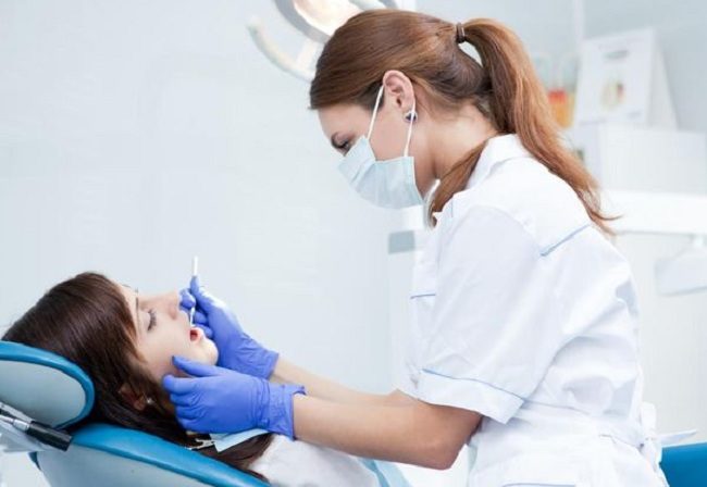 Женщина на приеме у стоматолога в белом халате