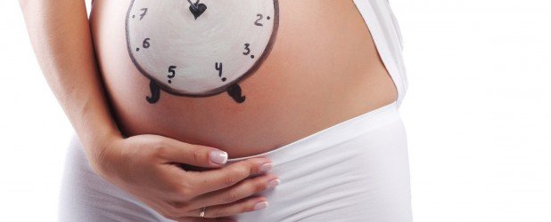 На беременном животе нарисованы часы