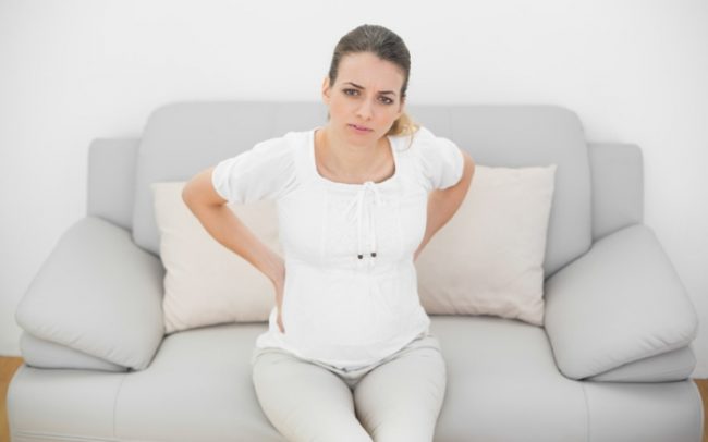 Заболевание позвоночника у беременной женщины в белой одежде