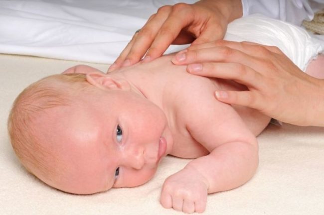 Новорождённый лежит на животе и массаж