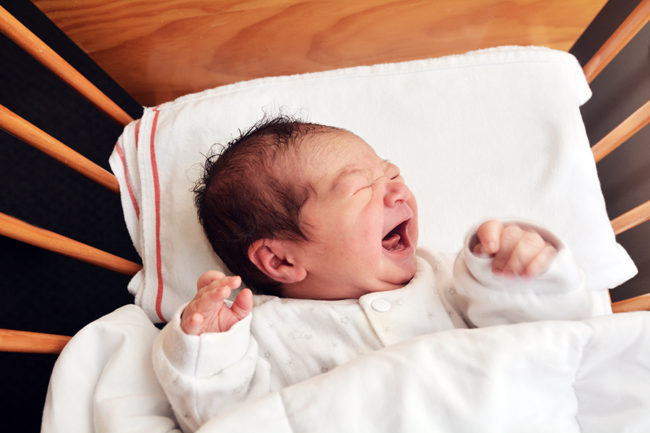 Новорождённый плачущий в кроватке 