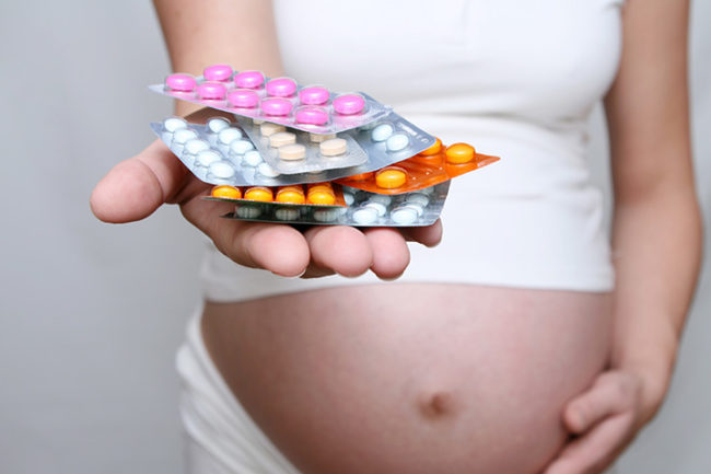 Разноцветные таблетки на руке у беременной женщины