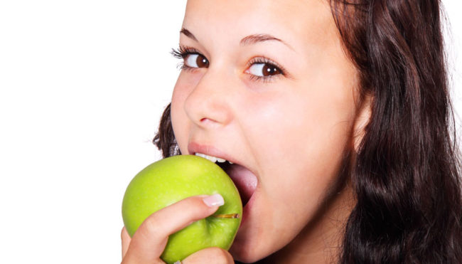 Женщина ест зелёное яблоко
