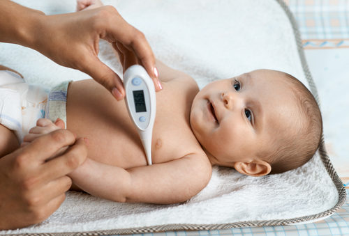 Новорождённому ребёнку измеряют температуру подмышкой электронным градусником