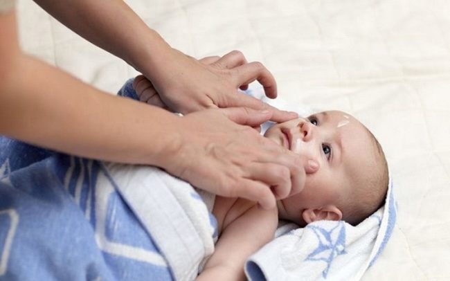 Нанесение крема на лицо новорождённого