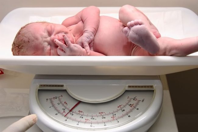 Новорождённый малыш на весах