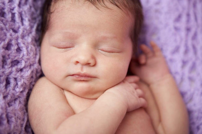 Новорождённый сладко спит сложа ручки