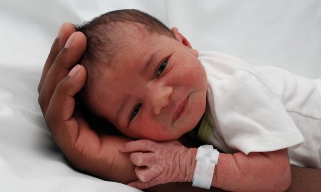 Новорождённый малыш с белой повязкой