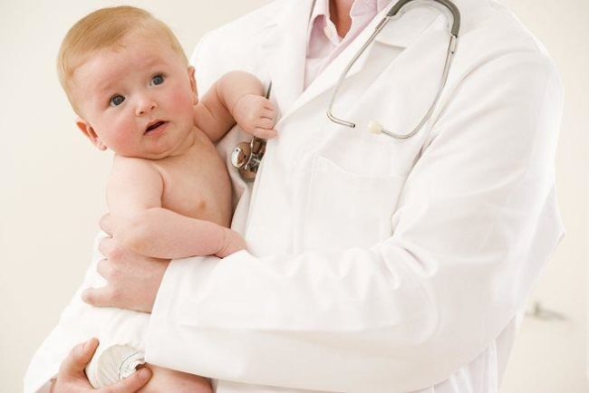 Новорождённый на руках педиатра на осмотре