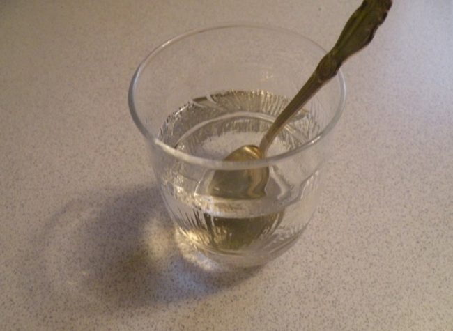 Тёплая кипячёная вода в стакане с ложкой