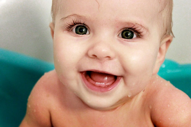 Мокрый малыш с карими глазами, у которого режутся зубки