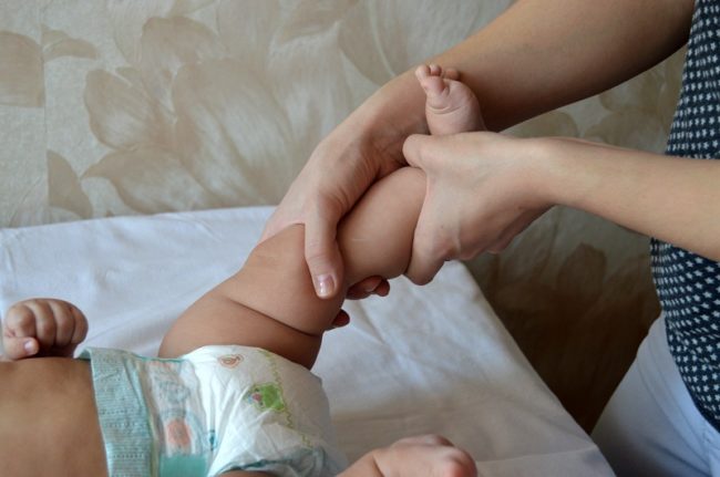 Специалист делает массаж ребёнку при вальгусной деформации стопы