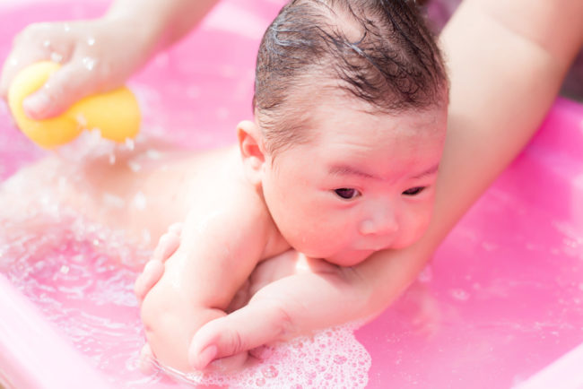Родители подмывают малыша в тазике с водой