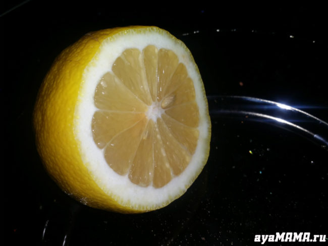 Порезанный наполовину лимон с семечком на тарелке