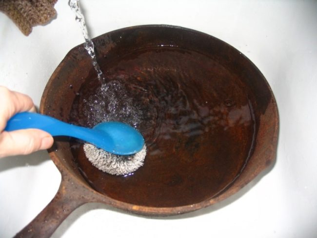 Чистка грубой щёткой ржавой сковороды от ржавчины проточной водой
